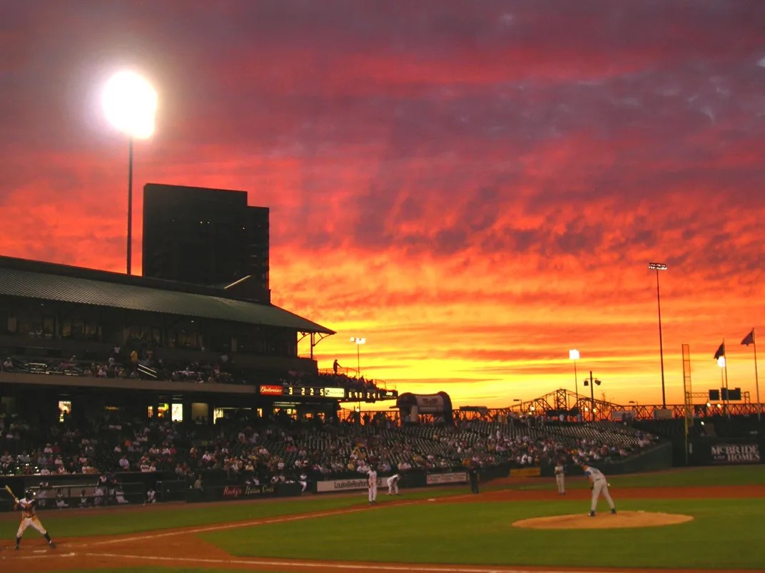 the sun sets over a baseball stadium