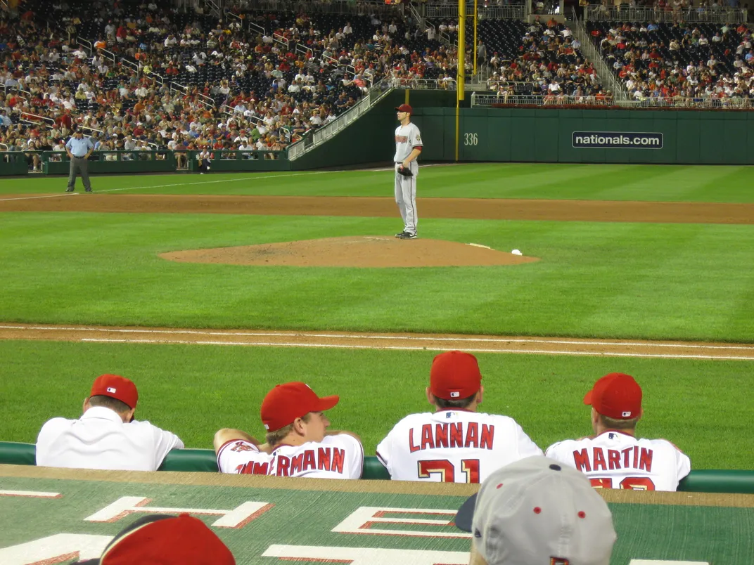 baseball players look out at the pitcher from the dugout