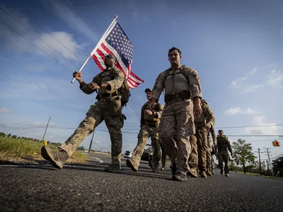 A service member carries a flag and leads his comrades at Joint Base McGuire-Dix-Lakehurst as they march in remembrance of 9/11 victims. More than 40 veterans died in the attacks.

