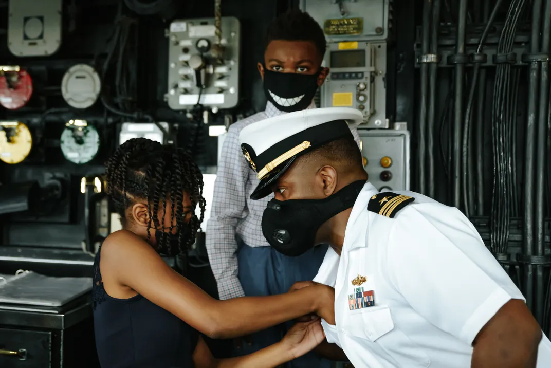 a Sailor has a medal pinned on his shirt by his daughter