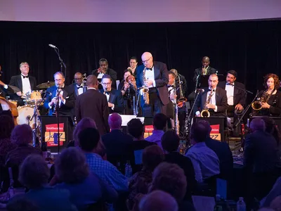 A group of jazz musicians perform on a stage to a live audience